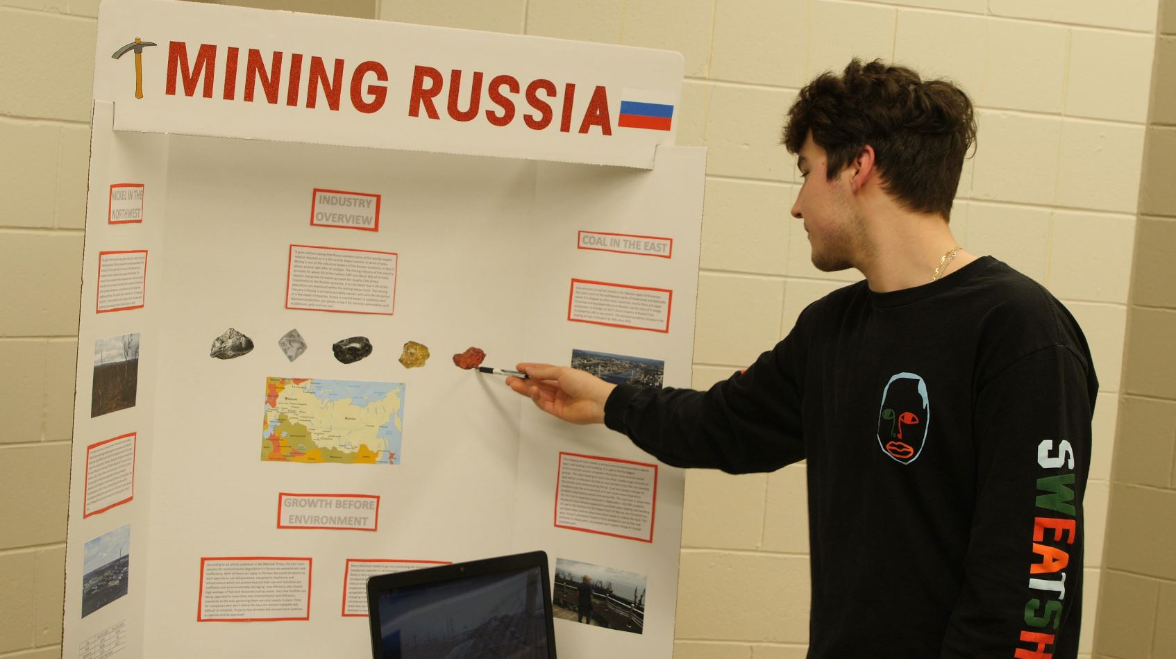 Photo of a student pointing to his board during tradeshow