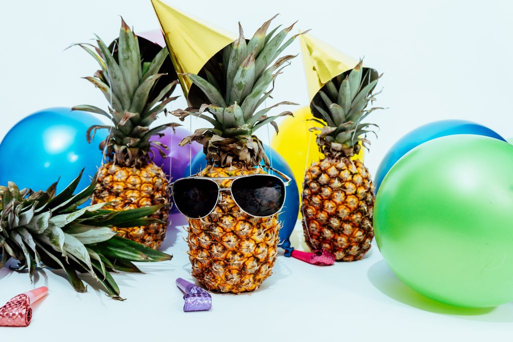 Pineapple with sunglasses, balloons, party hats